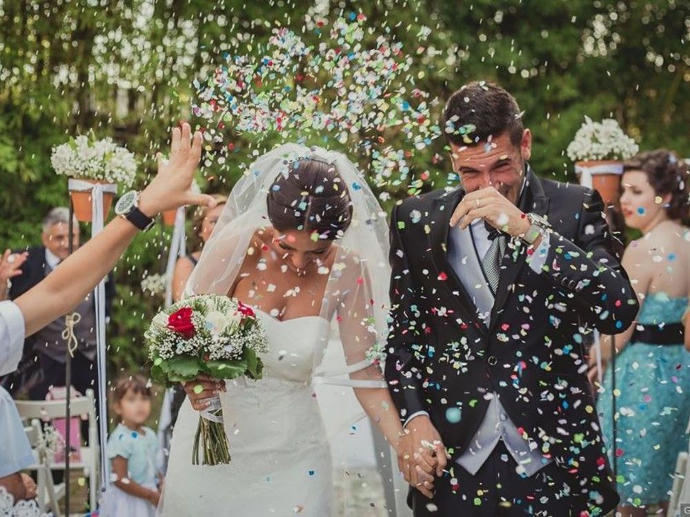 Novios recien casados, invitados tiran confeti.